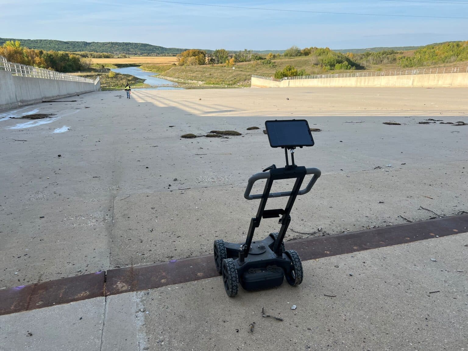 Technician pushing a Proceq GS8000 along a paved roadside while watching the scan on a tablet